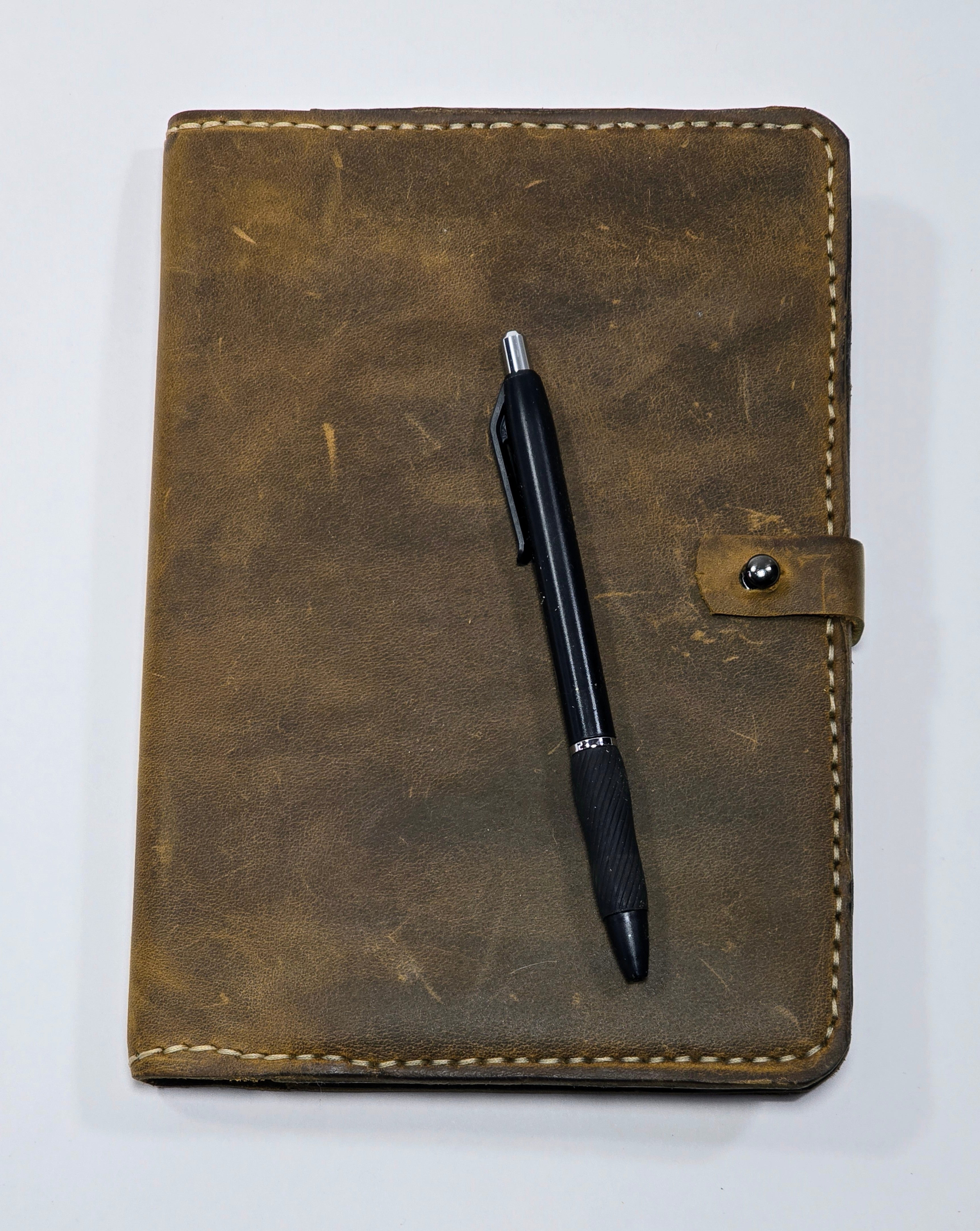 Brown leather journal cover with a pen on a white background