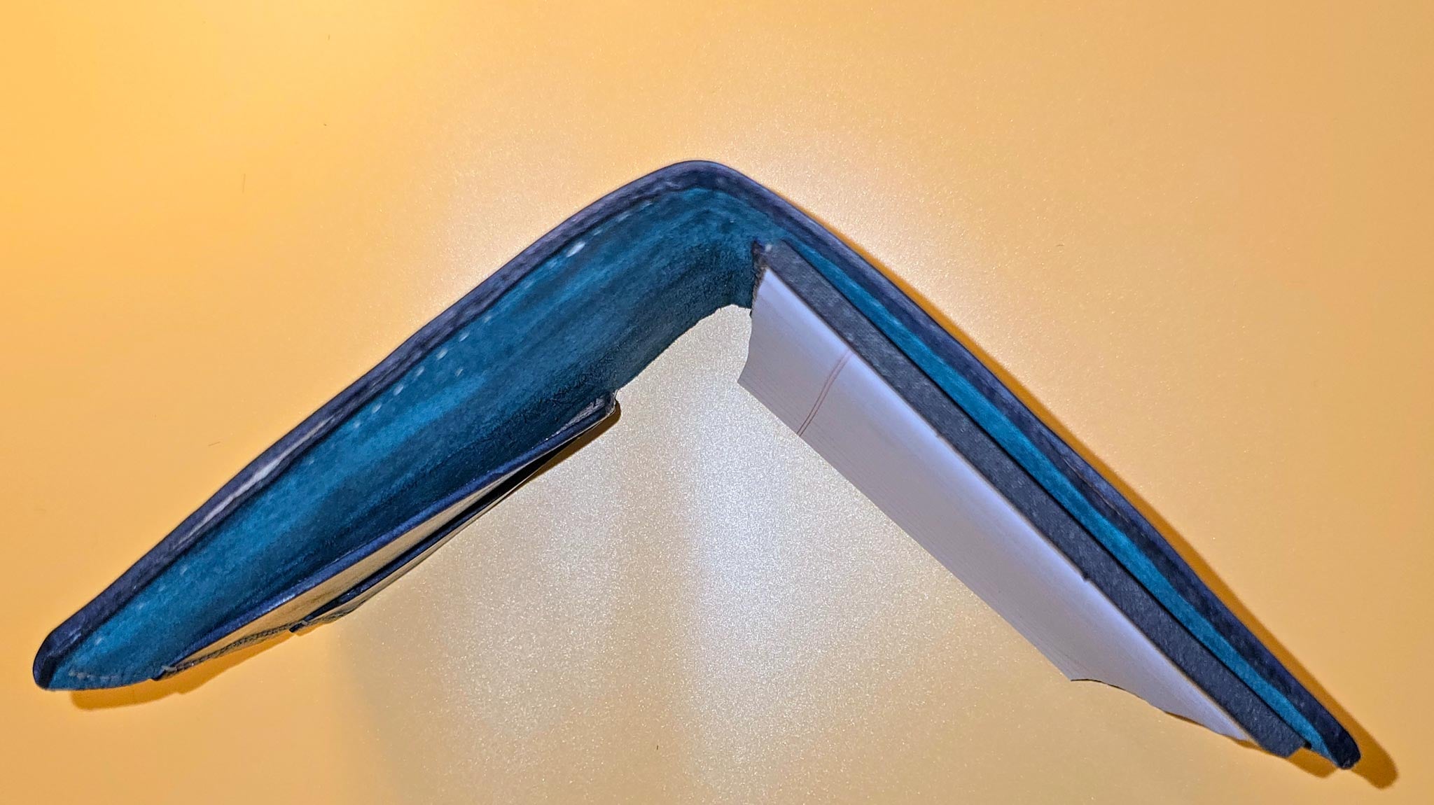 End view of open Hand-dyed leather mini padfolio with a unique, rich finish standing on a yellow background
