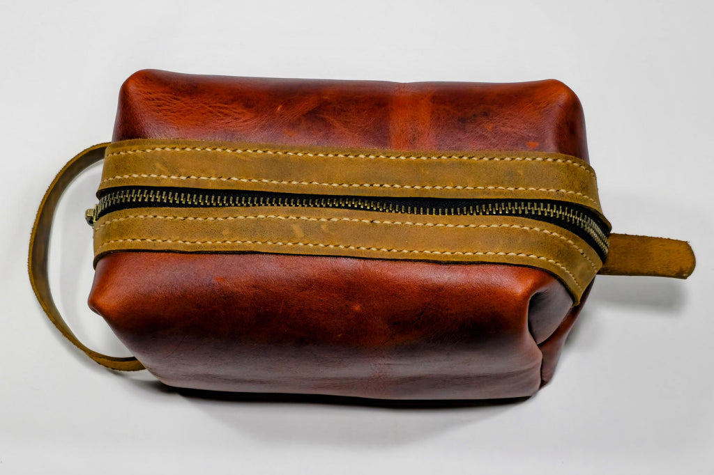 Burgundy leather toiletry bag with brown zipper on a white background
