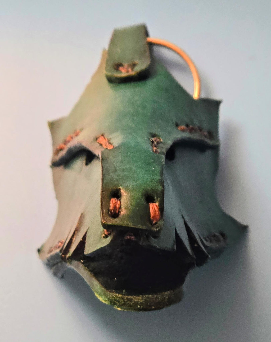 Close-up of a handmade leather dragon key fob showing intricate scale texture and rustic green finish.