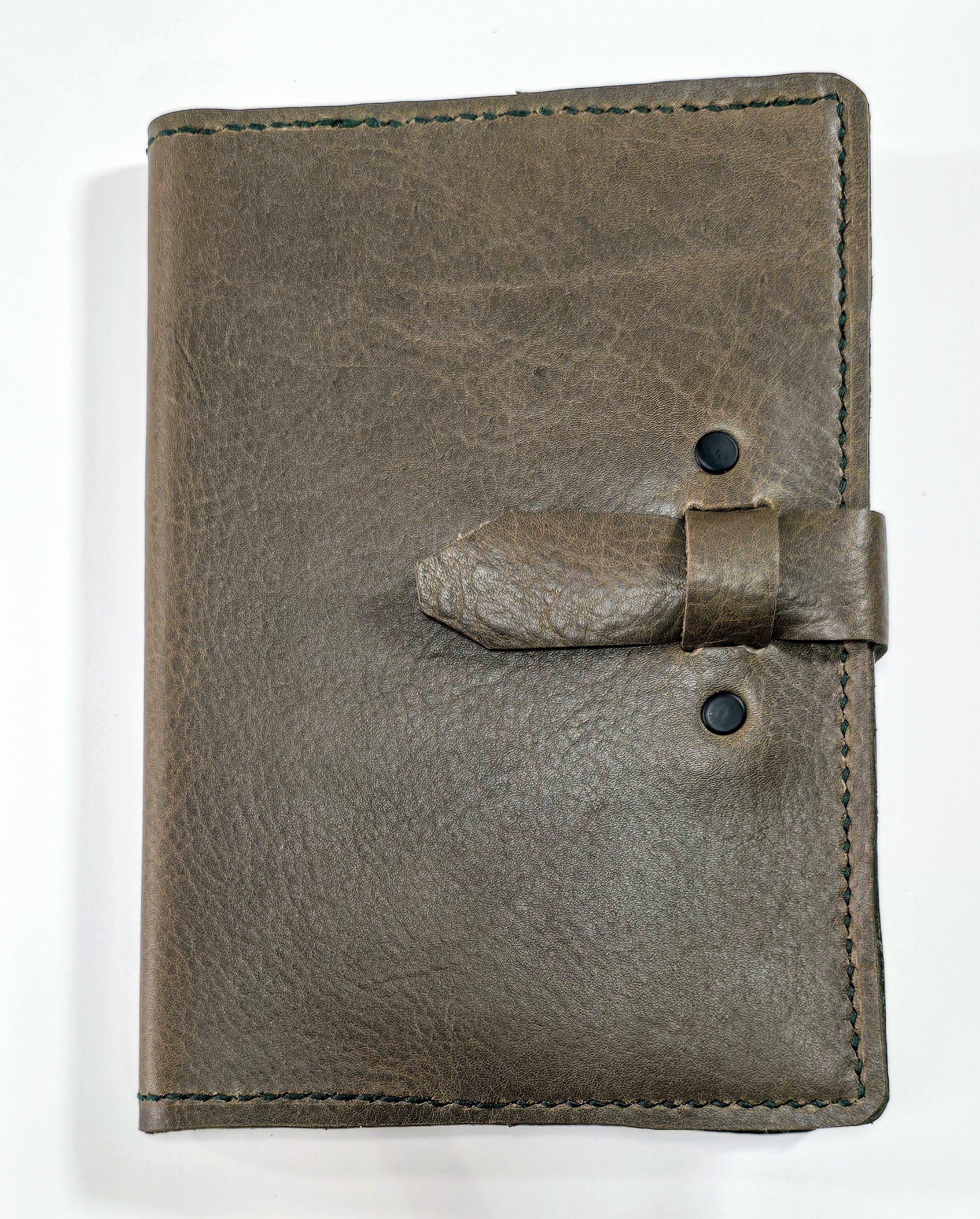 Brown embossed leather journal cover  with a strap closure on a white background
